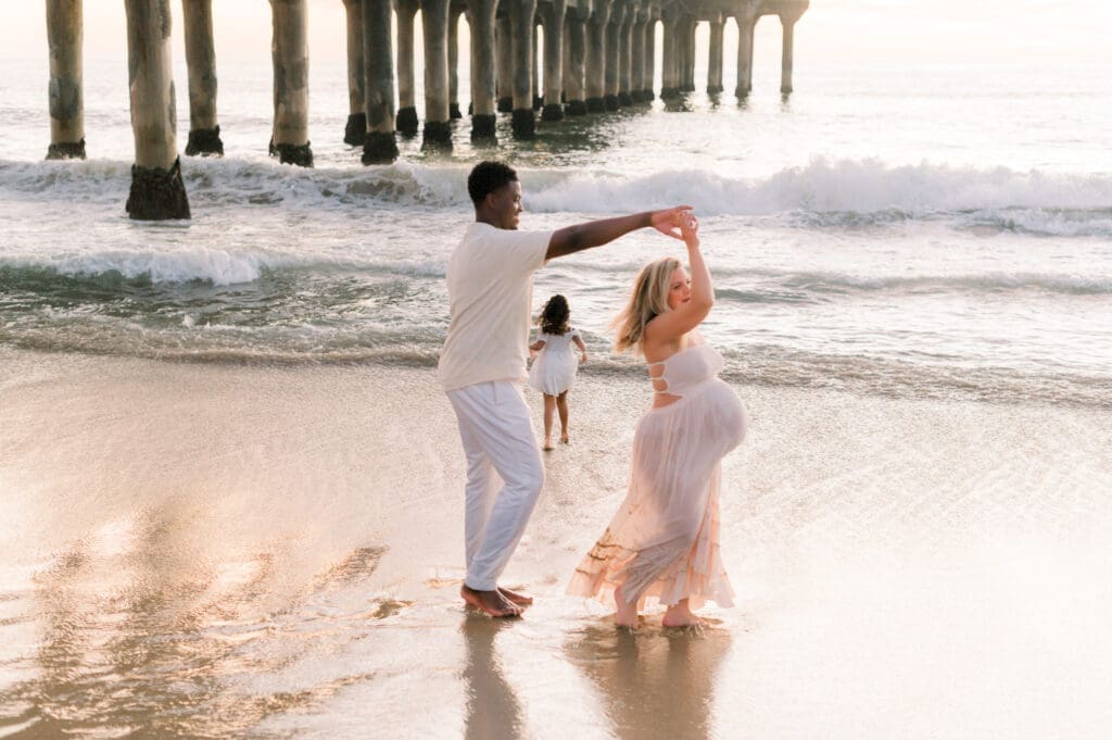 A Los Angeles maternity session featuring a couple dancing on the beach at sunset.