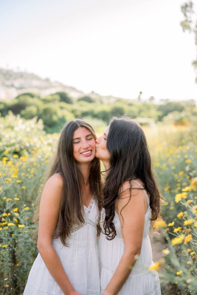 A mom kisses her daughter's cheek as they pose in the wildflowers in Palos Verdes.
