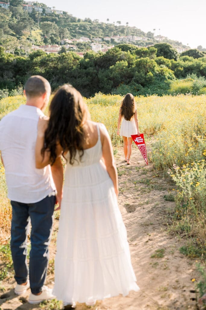 A Los Angeles senior photo session featuring a mom and dad watching their senior daughter walk away with her college banner.