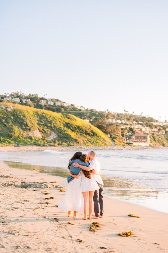 A family hugs on the beach during a Los Angeles senior photo session.