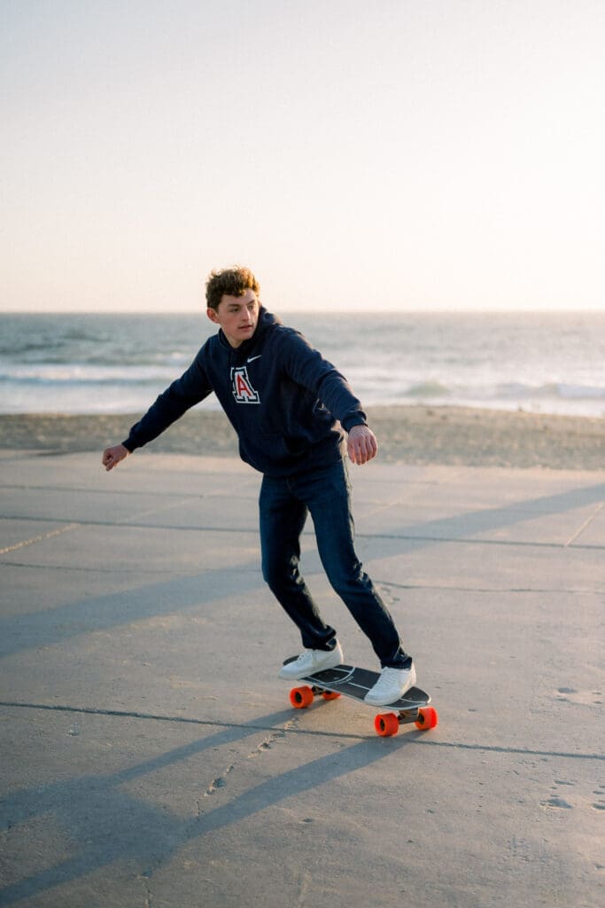 A boy skateboards at the beach during his Los Angeles senior photo session.