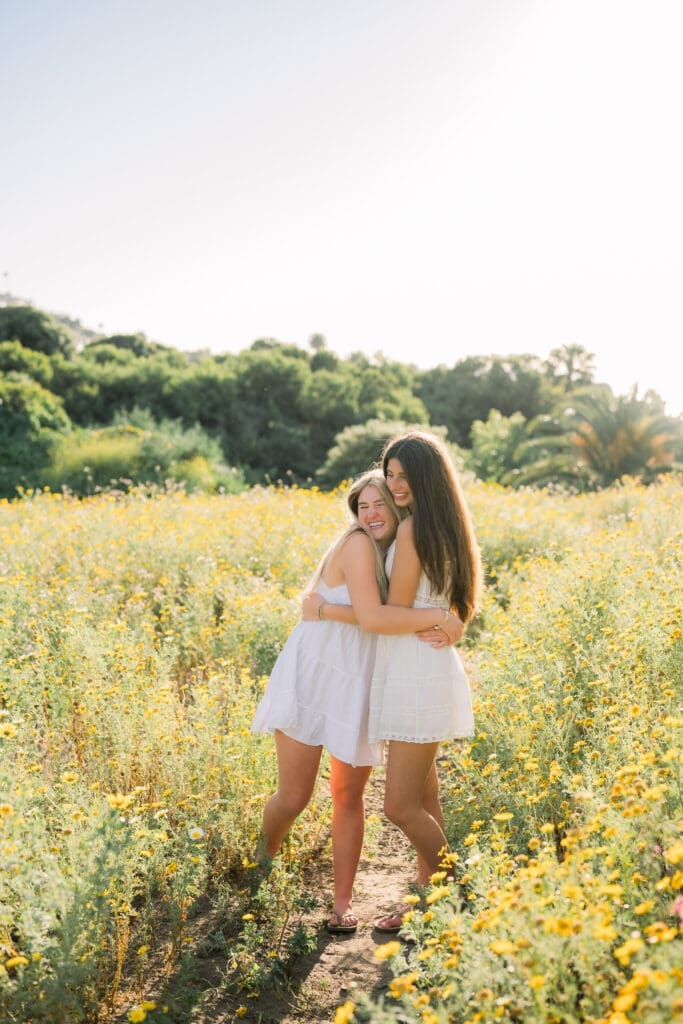 Best friends hugging in a field of wildflowers during their Los Angeles senior photo session.