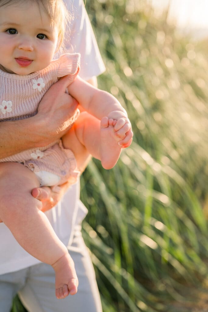A little girl playing with her feet while taking family portraits in spring in Los Angeles.