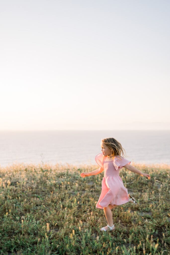 A little girl runs freely along the Palos Verdes Cliffs while taking spring family portraits in Los Angeles.