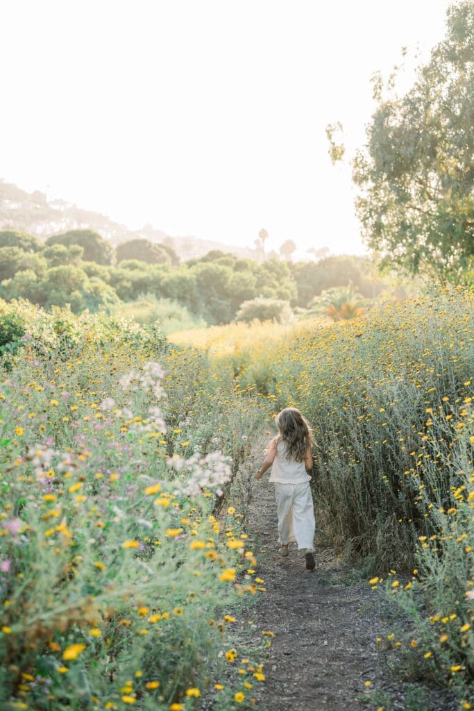 A little girl running through the wildflowers during a spring family portrait session in Los Angeles.
