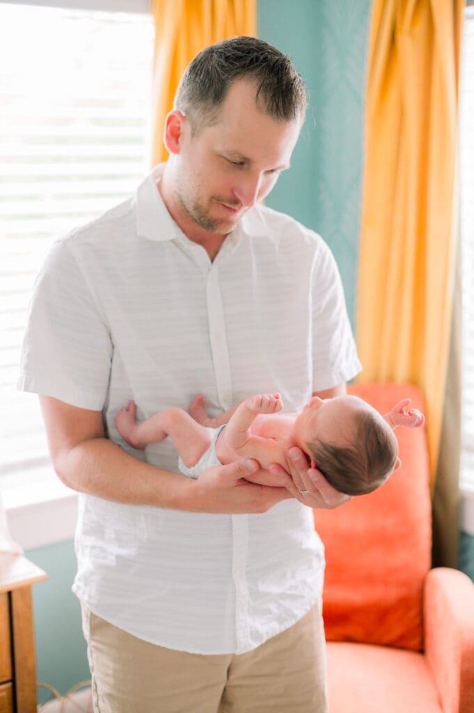 A dad holding his newborn baby wearing a diaper.