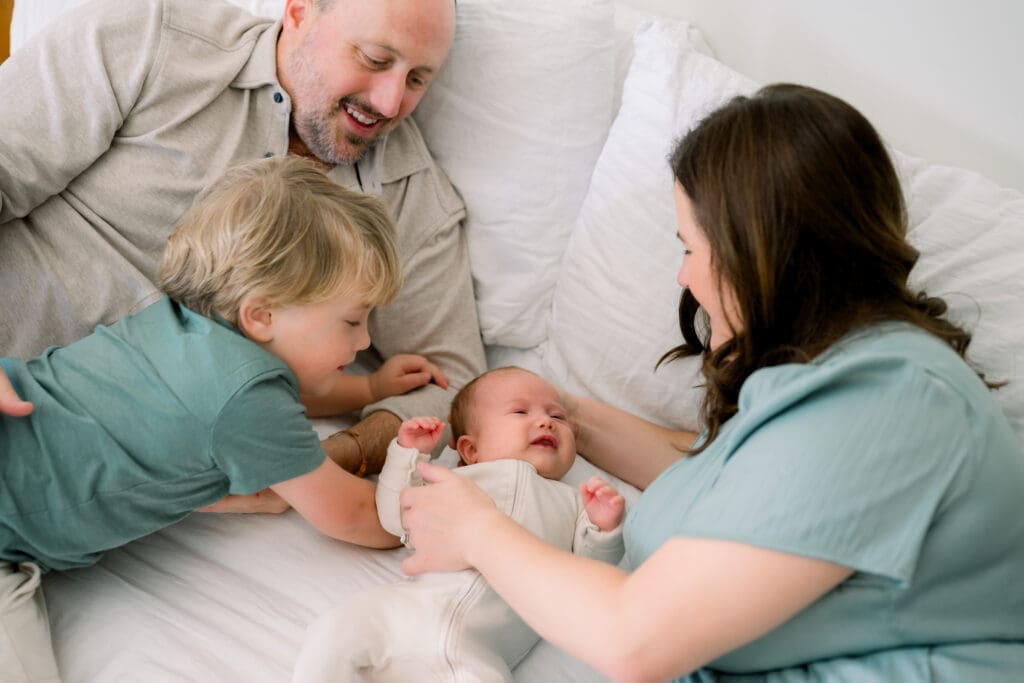 A family of 4 loving on their newborn baby boy at home.