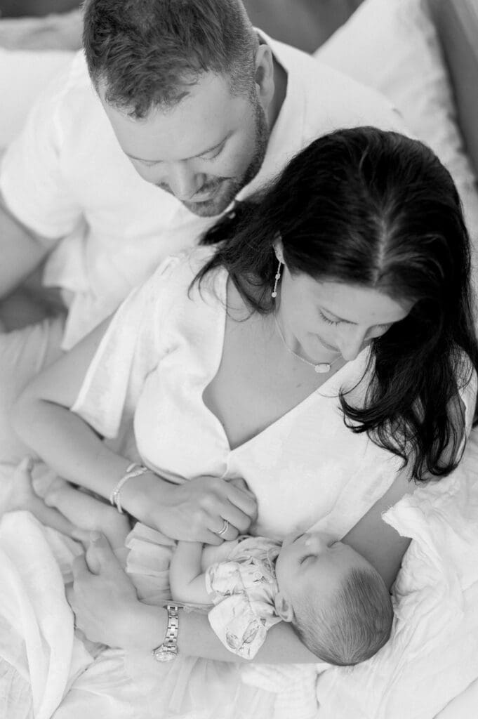 Mom and dad lovingly looking at their newborn baby sleep.