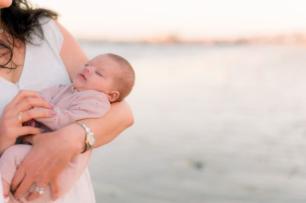A newborn baby sleeping peacefully during her outdoor newborn photo session at the beach.