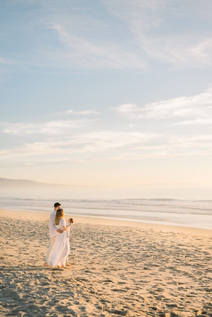 A beautiful photo of new parents walking with their newborn baby on a South Bay beach.