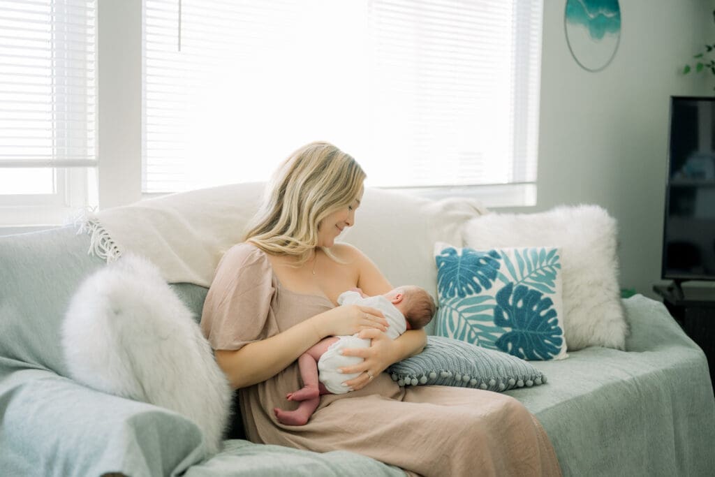 A mom breastfeeding her newborn baby on a couch.