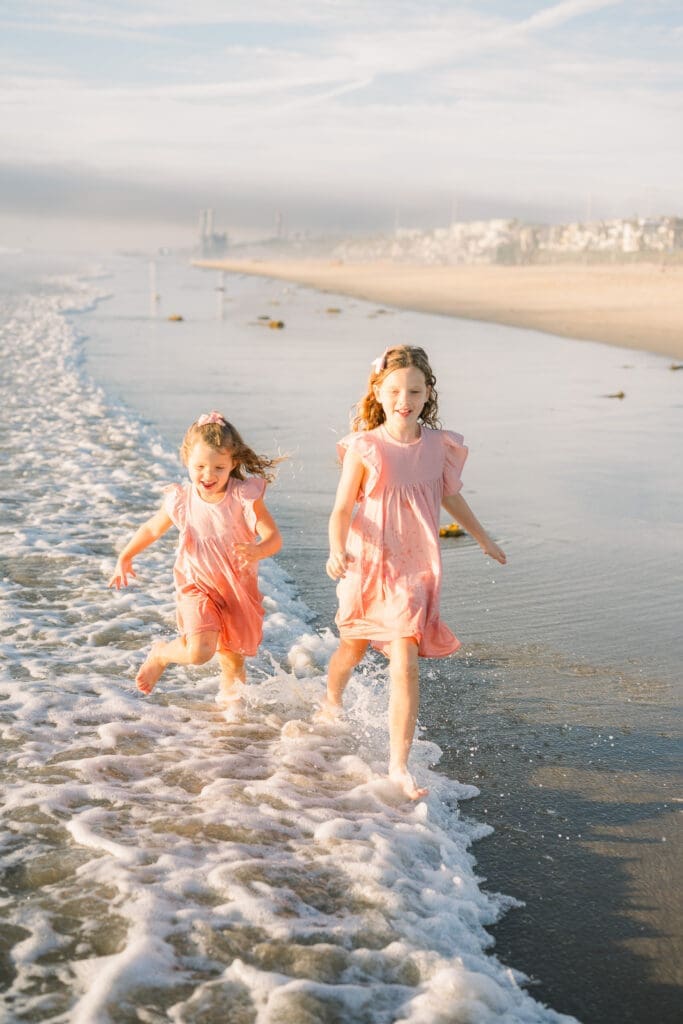 Girls running on Manhattan beach during their family photos taken by a South Bay photographer.