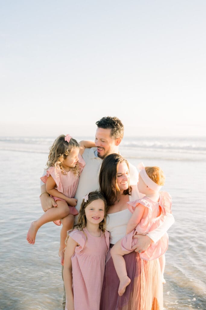 A family laughing on Manhattan Beach while they take family photos.
