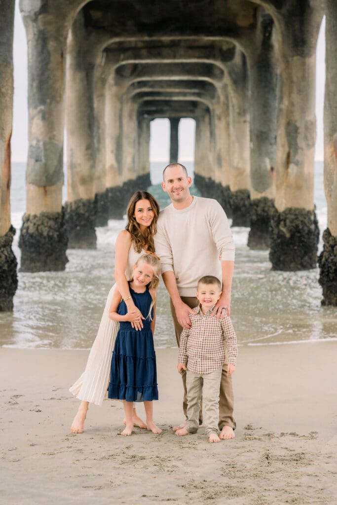 A family taking family photos under the iconic Manhattan Beach pier.