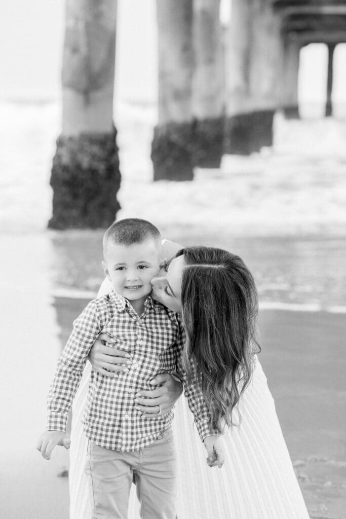 A mom kissing her son under the Manhattan Beach pier.