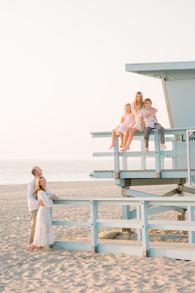 A family hanging out on a lifeguard tower in Hermosa Beach at sunset taking family photos.