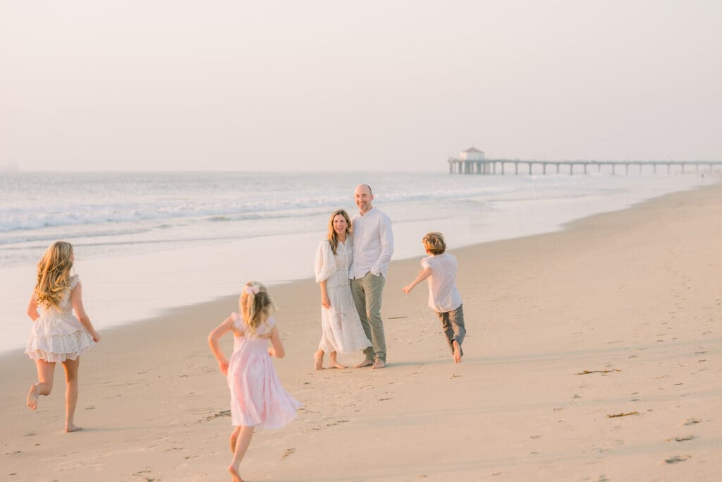 A family of 5 running on the beach at sunset during their family photo session in the South Bay.