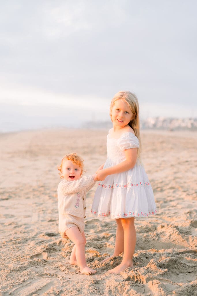 Sisters smiling on the beach for family photos in the South Bay.