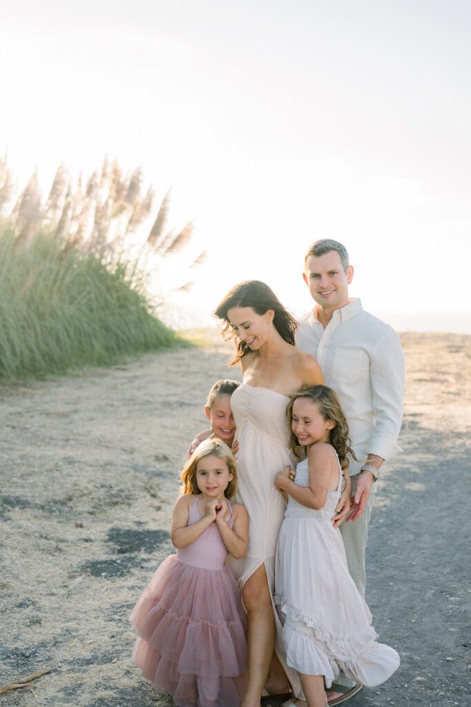 A family snuggling while taking family photos in Palos Verdes at sunset.