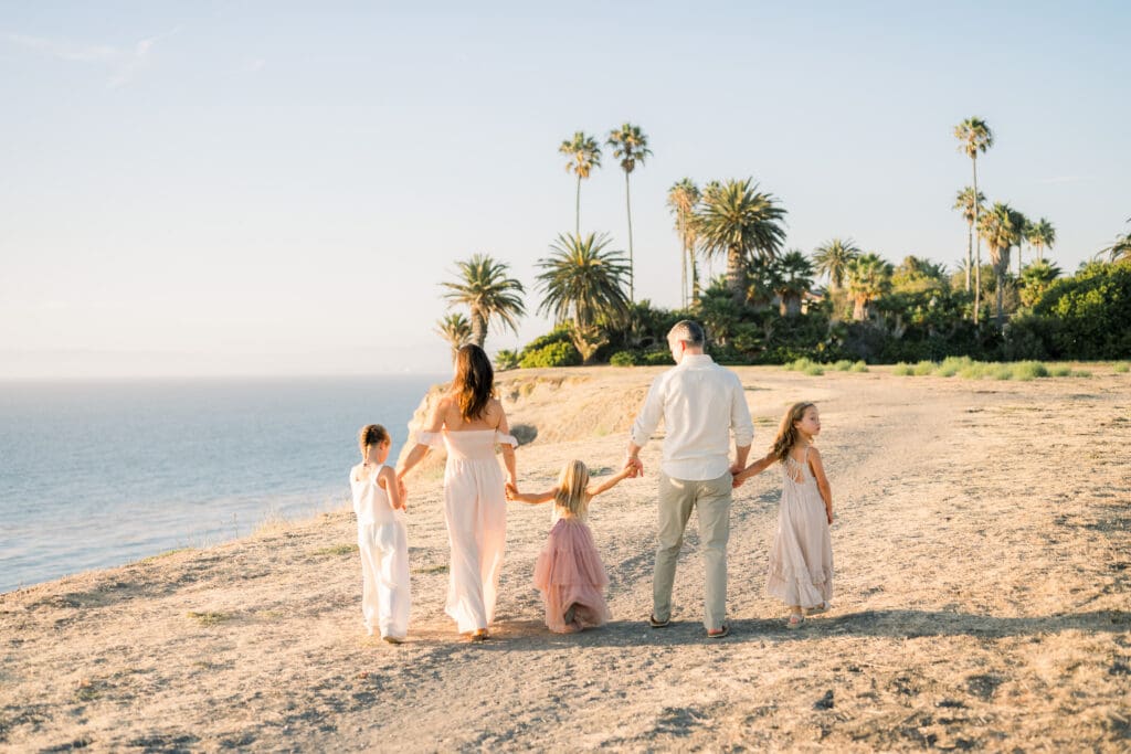 A family walking along the Palos Verdes cliffs with palm trees in the background.