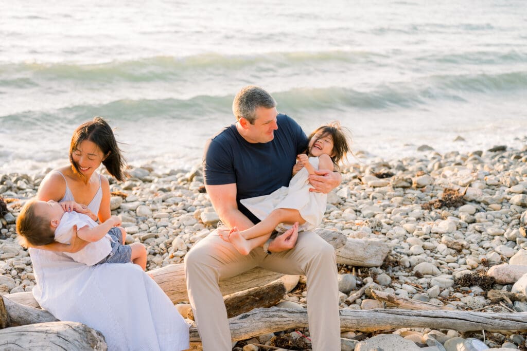 A family of 4 laughing on RAT beach in the South Bay while taking family photos.