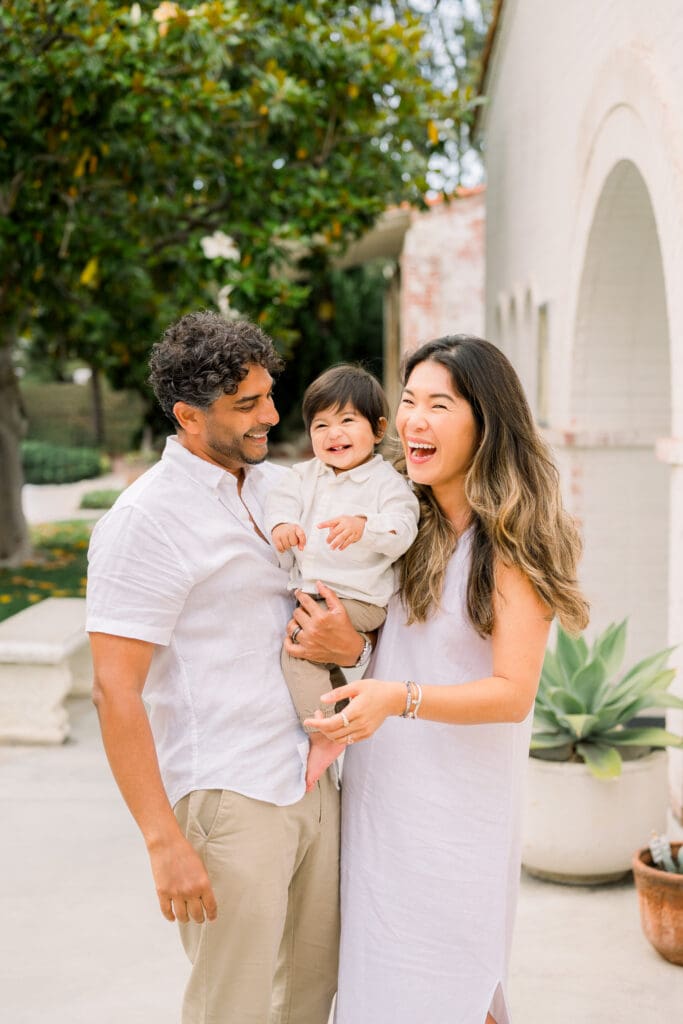 Mom, dad, and toddler laughing together.