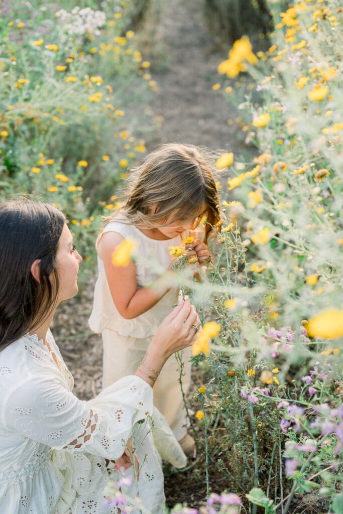 A little girl and her mom smelling the yellow wildflowers during their photo session in Palos Verdes.