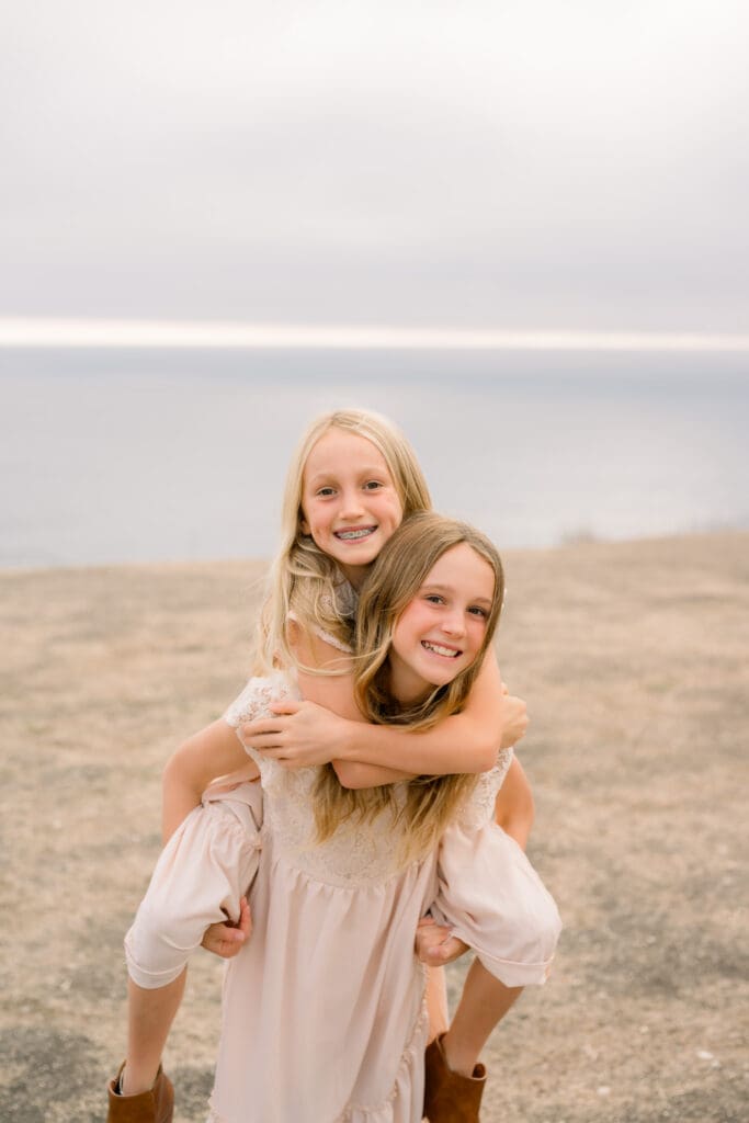 Sisters doing piggy back rides during their family photos.