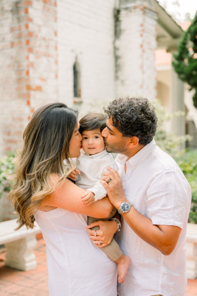 Mom and dad kissing their son's cheeks during their family photos at one of the best South Bay family photo locations of St. Francis Church.