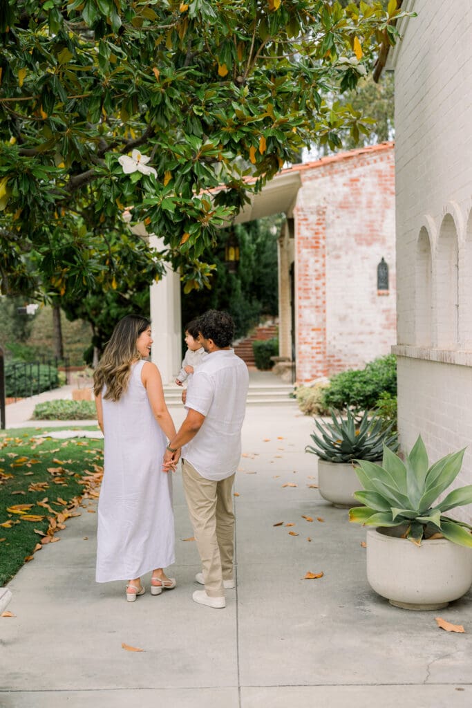 A family walking together along the St. Francis Church buildings taking family photos.
